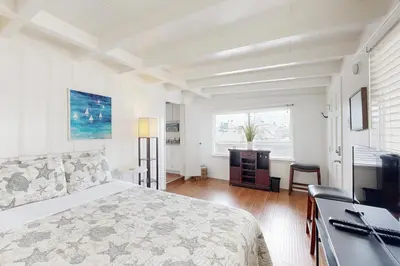 a white bedroom with a bed and a television at Sailaway Cabin in Ventura