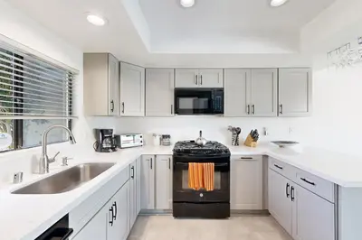 a kitchen with white cabinets and a sink and an oven at Gateshead Haven in Oxnard