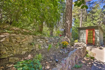 a stone wall with a red door in a garden at Cozy Skyforest Cabin about 1 Mi to Lake Arrowhead! in Skyforest