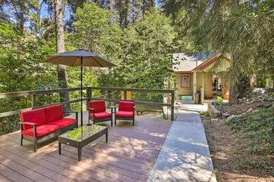 a patio with two chairs and an umbrella at Cozy Skyforest Cabin about 1 Mi to Lake Arrowhead! in Skyforest