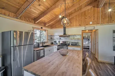 a large kitchen with a wooden ceiling and a wooden table at Newly Renovated Lake Arrowhead Cabin with Deck! in Lake Arrowhead