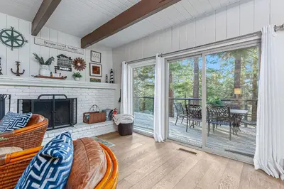 a living room with a fireplace and a screened porch at Serene Cabin in Lake Arrowhead