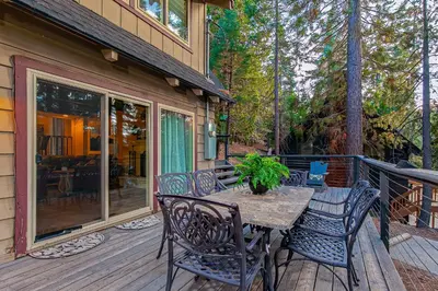 a porch with a table and chairs on a deck at Serene Cabin in Lake Arrowhead