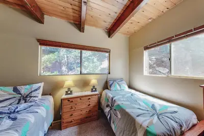 a bedroom with two beds and a dresser and two windows at Dragon's Lair in Lake Arrowhead