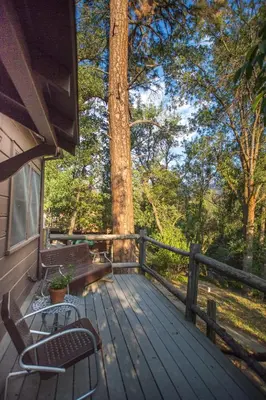 a wooden deck with two chairs and a bench on it at Quiet Mind Lodge, Spa & Retreat Sequoias in Kernville