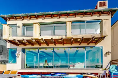 a house with large glass windows and a deck at Breakers Way Adventure in Carpinteria