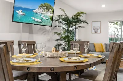 a wooden table with chairs and a tv on a wall at The Avalon - 35 Percent Off March! in Los Angeles