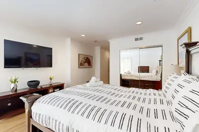a white bedroom with a large bed and a mirror at Tullis Charm in Los Angeles