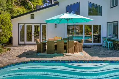 a patio with a table and umbrella next to a swimming pool at Tullis Charm in Los Angeles