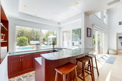 a kitchen with a counter with stools and a large window at Tullis Charm in Los Angeles