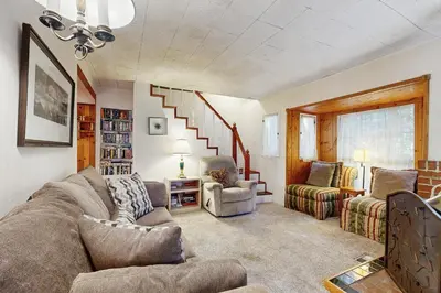 a living room with a couch and chairs and stairs at The Cottage in Lake Arrowhead