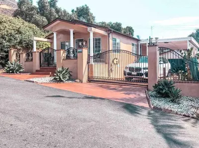 a house with a gate and a car in the driveway at Cozy beach home walking distance from ocean in Ventura