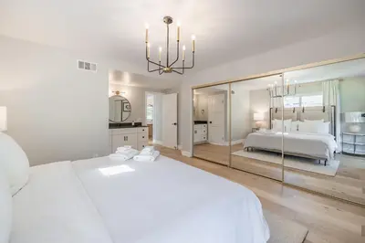 a white bedroom with a bed and a large mirror at #Marbella Lane - Cozy Modern Home with Relaxing Design & Pool in Fullerton
