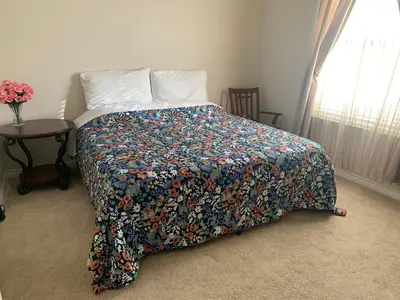 a bedroom with a bed with a floral bedspread and a table at HighEnd Rooms in Mansion in Riverside