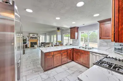 a large kitchen with wooden cabinets and marble counter tops at Bright California Home with Patio Less Than 1 Mi to Hiking! in Corona