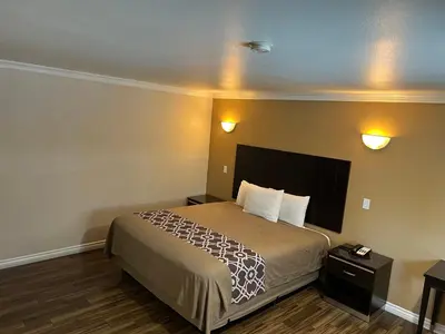 a hotel room with a bed and two lights on the wall at Walnut Inn & Suites West Covina in West Covina
