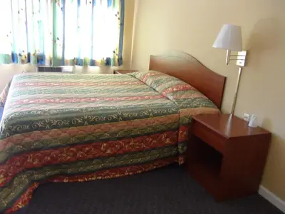 a hotel room with a bed and a night stand at Desert Inn Motel in Corona