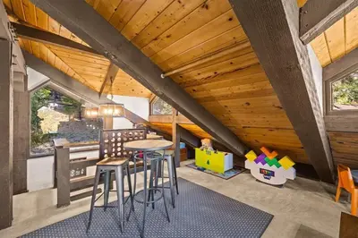 an attic room with a table and stools at The Lake Chalet in Crestline