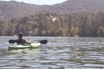 a person is sitting in a kayak on a lake at The Lake Chalet in Crestline