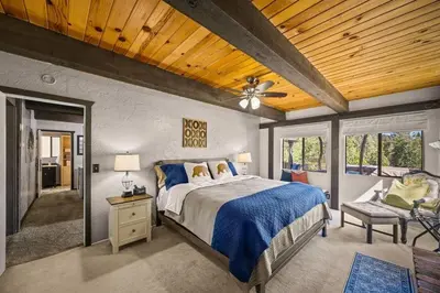 a bedroom with a large bed and a wooden ceiling at The Lake Chalet in Crestline