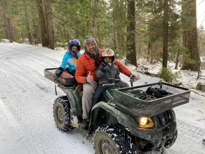 a man and two children riding on a four wheeler in the snow at Glamping property in Panorama Heights