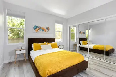 a bedroom with two beds with yellow sheets and windows at Adorable 3 bedroom with Jacuzzi & more in Los Angeles