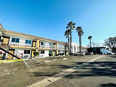 a parking lot in front of a hotel with palm trees at Casa Blanca Hotel - Cypress, Buena Park in Cypress