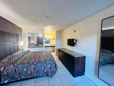 a bedroom with a bed and a dresser and a television at Casa Blanca Hotel - Cypress, Buena Park in Cypress