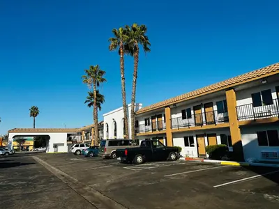 a parking lot in front of a hotel with palm trees at Casa Blanca Hotel - Cypress, Buena Park in Cypress