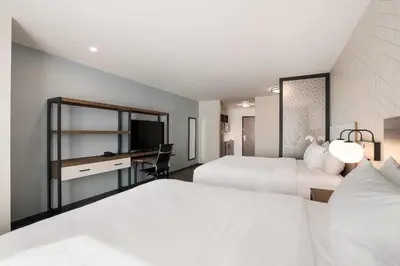 a hotel room with two beds and a desk at Everhome Suites Corona in Corona