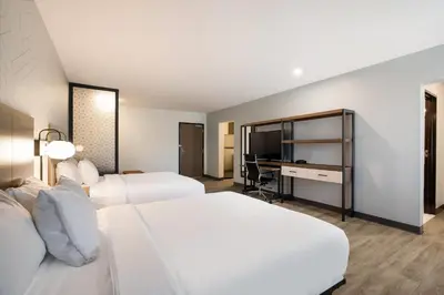 a hotel room with two beds and a television at Everhome Suites Corona in Corona
