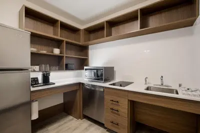 a kitchen with a sink and a refrigerator at Everhome Suites Corona in Corona