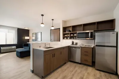 a kitchen with a sink and a refrigerator at Everhome Suites Corona in Corona