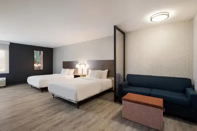 a hotel room with two beds and a couch at Everhome Suites Corona in Corona