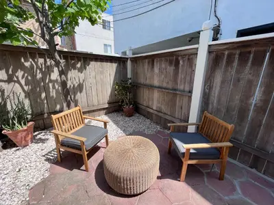 a patio with two chairs and a table and a fence at The Craftsman House in Venice Beach in Los Angeles
