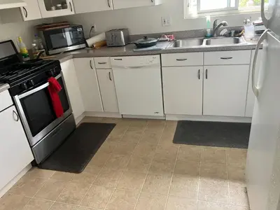 a kitchen with white cabinets and a stove and a sink at Nearby Beach House in El Segundo