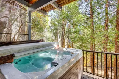 a hot tub on a deck with trees in the background at Spacious Retreat 13 Mi to Snow Valley Mtn Resort! in Lake Arrowhead
