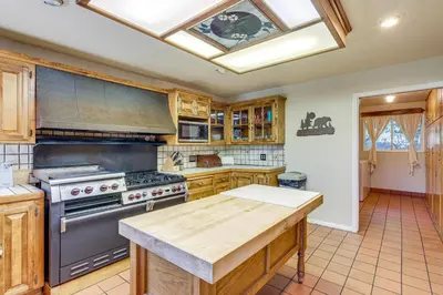 a kitchen with wooden cabinets and a stove top oven at Spacious Retreat 13 Mi to Snow Valley Mtn Resort! in Lake Arrowhead