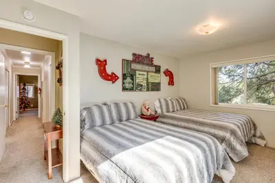 a bedroom with two beds and a child sitting between them at Spacious Retreat 13 Mi to Snow Valley Mtn Resort! in Lake Arrowhead