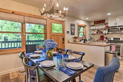 a dining room with a table and chairs and a kitchen at Steps to Lake Cabin with Deck in Lake Arrowhead in Lake Arrowhead