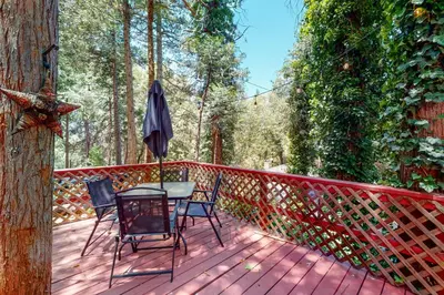 a wooden deck with a table and chairs and an umbrella at Top Town Retreat in Crestline