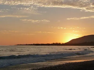 a beach with the sun setting on the water at The Green Haven, 1 Minute Walk to the Beach and Restaurants, King Beds, Beach Amenities in Ventura