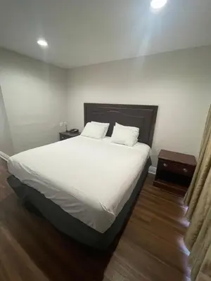 a bed with white sheets and pillows in a room at Lanai Motel in Alhambra