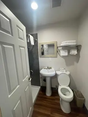 a bathroom with a white toilet and a sink at Lanai Motel in Alhambra