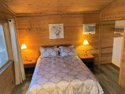 a bed in a wooden room with two lamps at Cozy Lake-View Lodge Near Village in Big Bear Lake