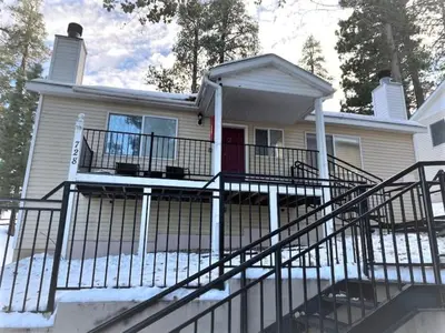 a white house with a staircase leading to the front door at Cozy Lake-View Lodge Near Village in Big Bear Lake