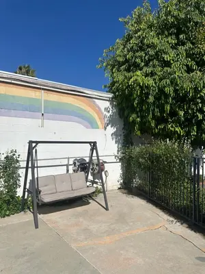 a porch swing with a rainbow in the background at Stardust inn in Azusa