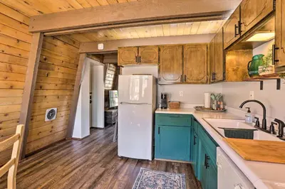 a kitchen with a white refrigerator and wooden cabinets at Pet-Friendly Cottage, Walk From Big Bear Village! in Big Bear Lake