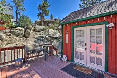 a red house with a dog sitting on a deck at Big Bear Cabin Close to Lake, Trails and Village! in Big Bear Lake