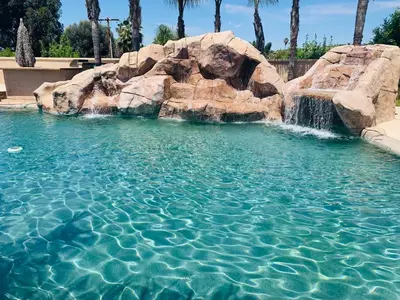 a swimming pool with a waterfall and rocks at LuxHome Suites in Mansion in Riverside
